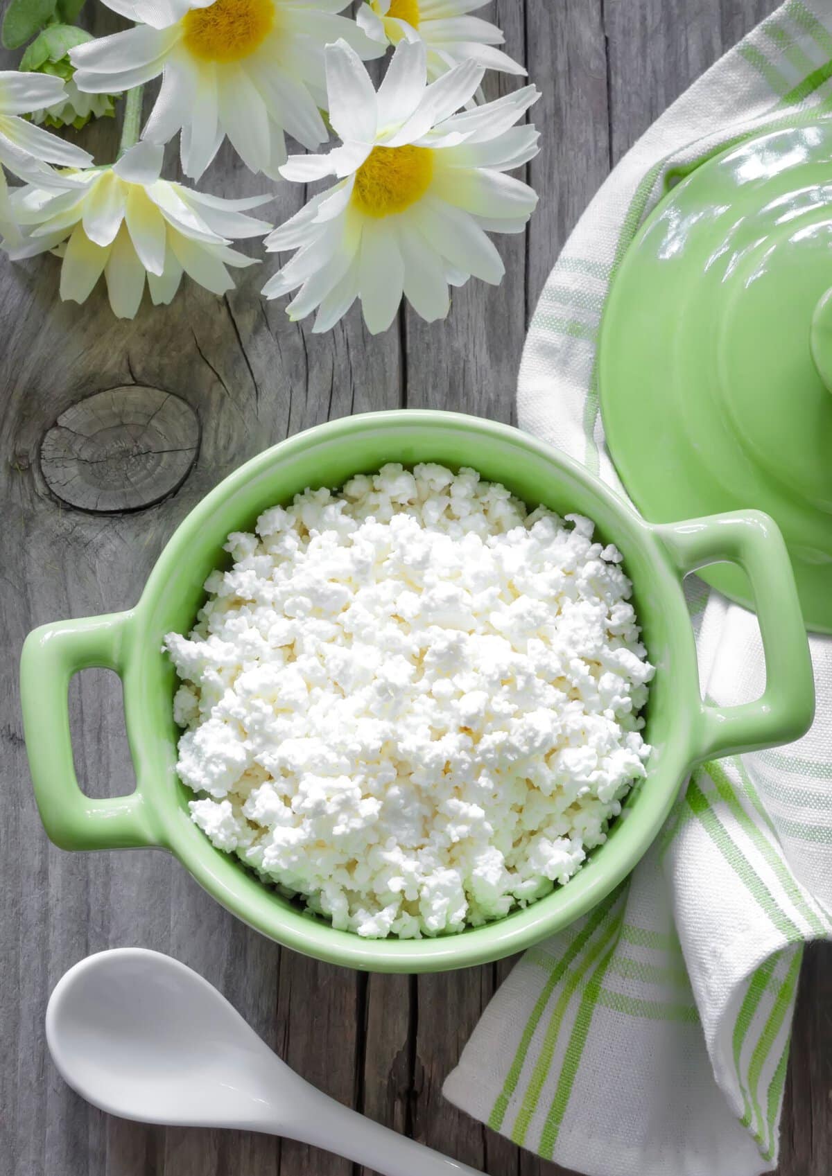 Cottage cheese in a green mini cocette on grey wood table.