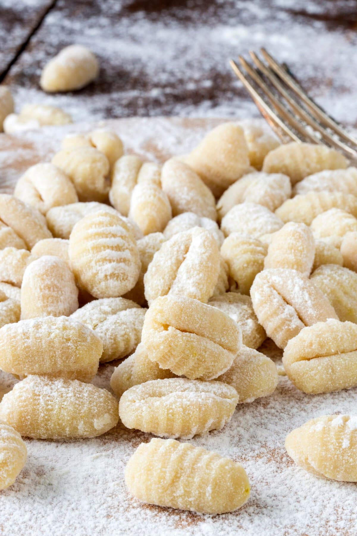 Potato gnocchi laying atop each other on floured table.