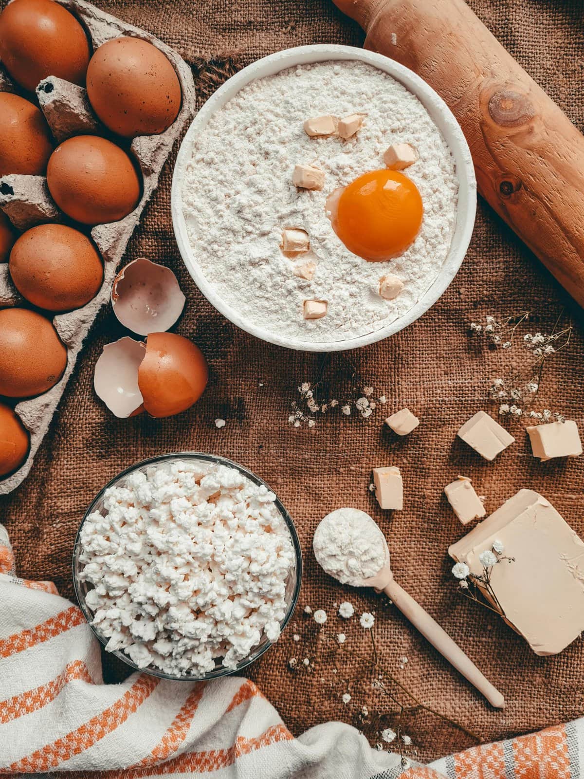 Flour, eggs, and cottage cheese on a brown table.