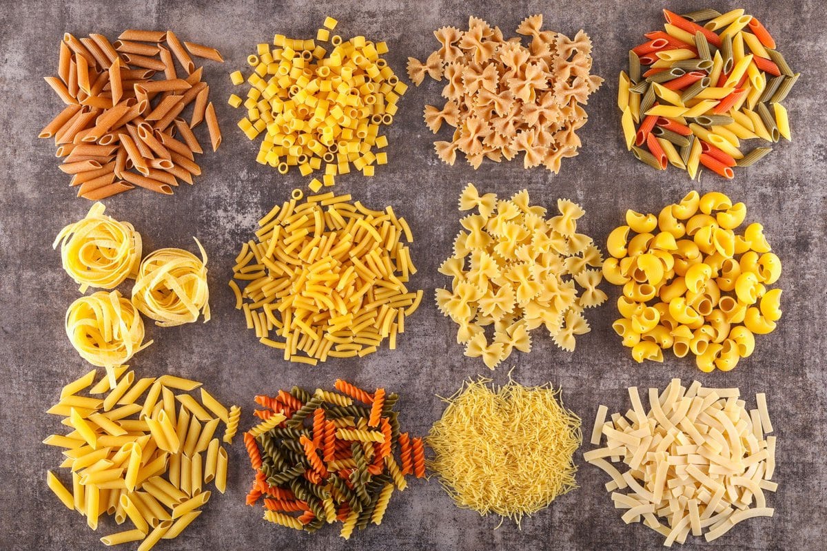 12 types of pasta laid out on gray background.