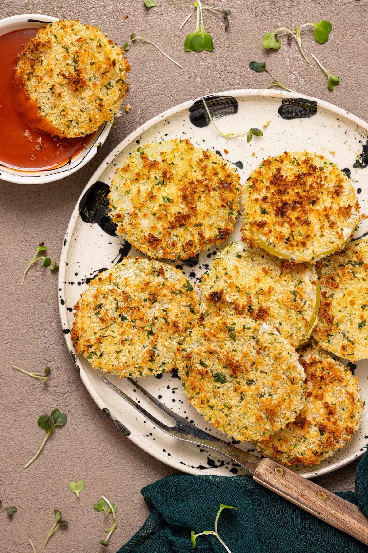 Fried green tomatoes on a plate with one dipped in  red sauce.