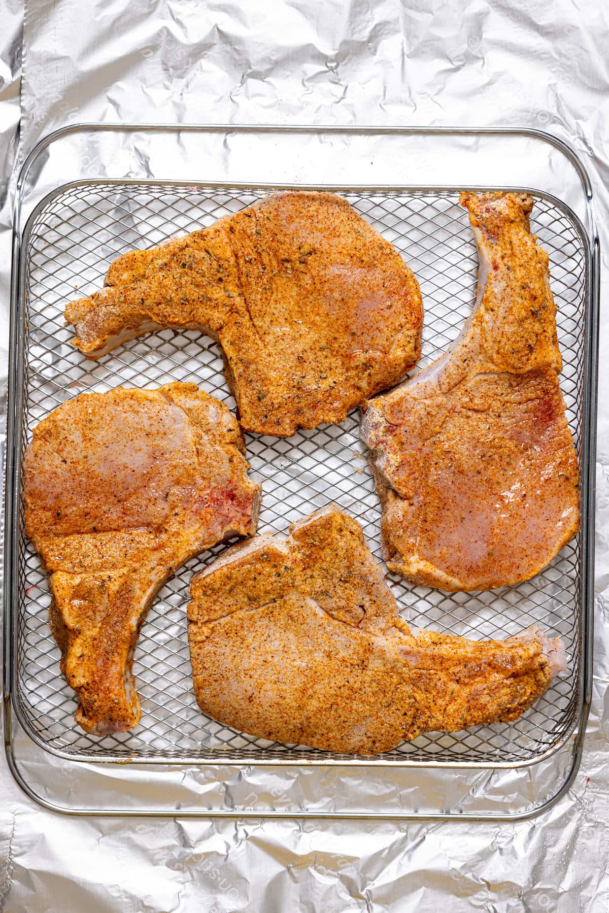 Air Fried pork chops on wire rack on foil paper.