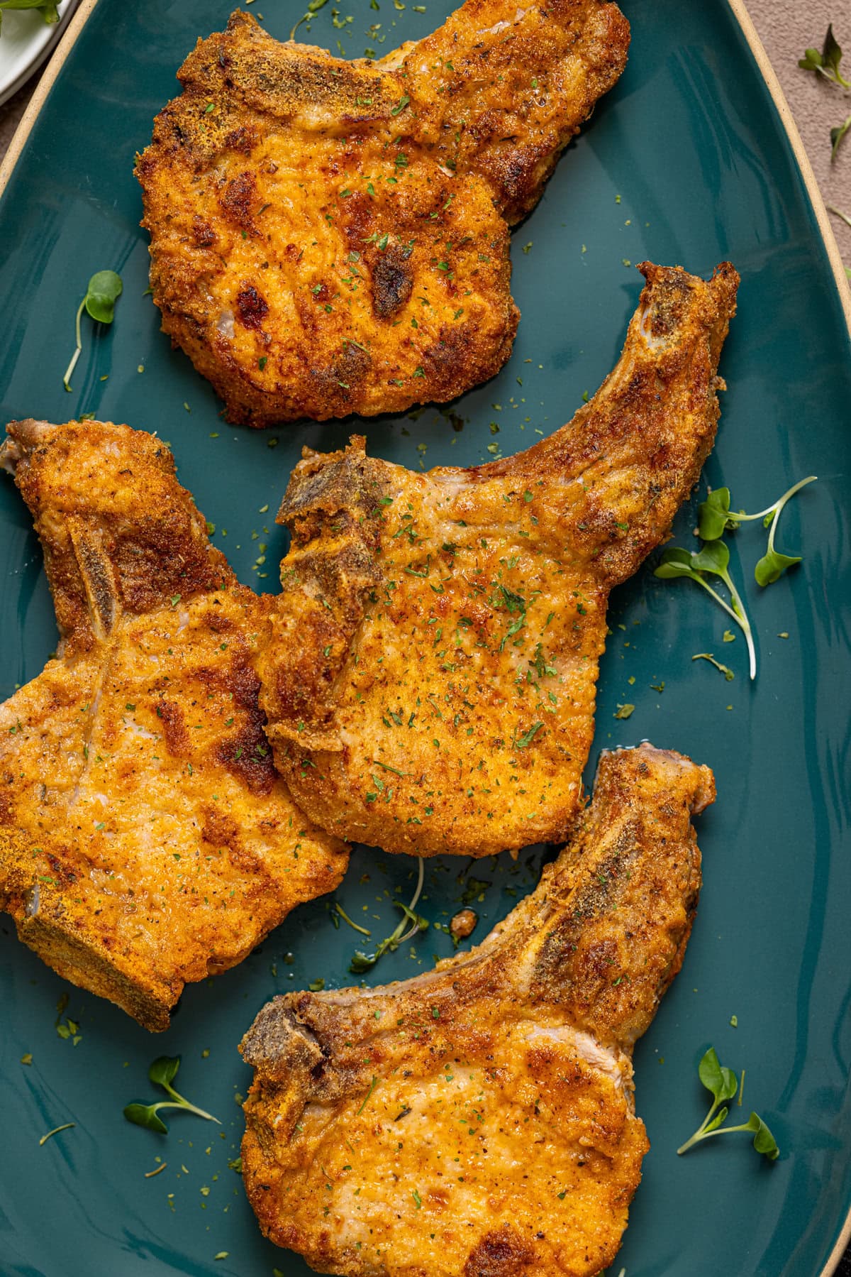 Air fryer pork chops on green plate.