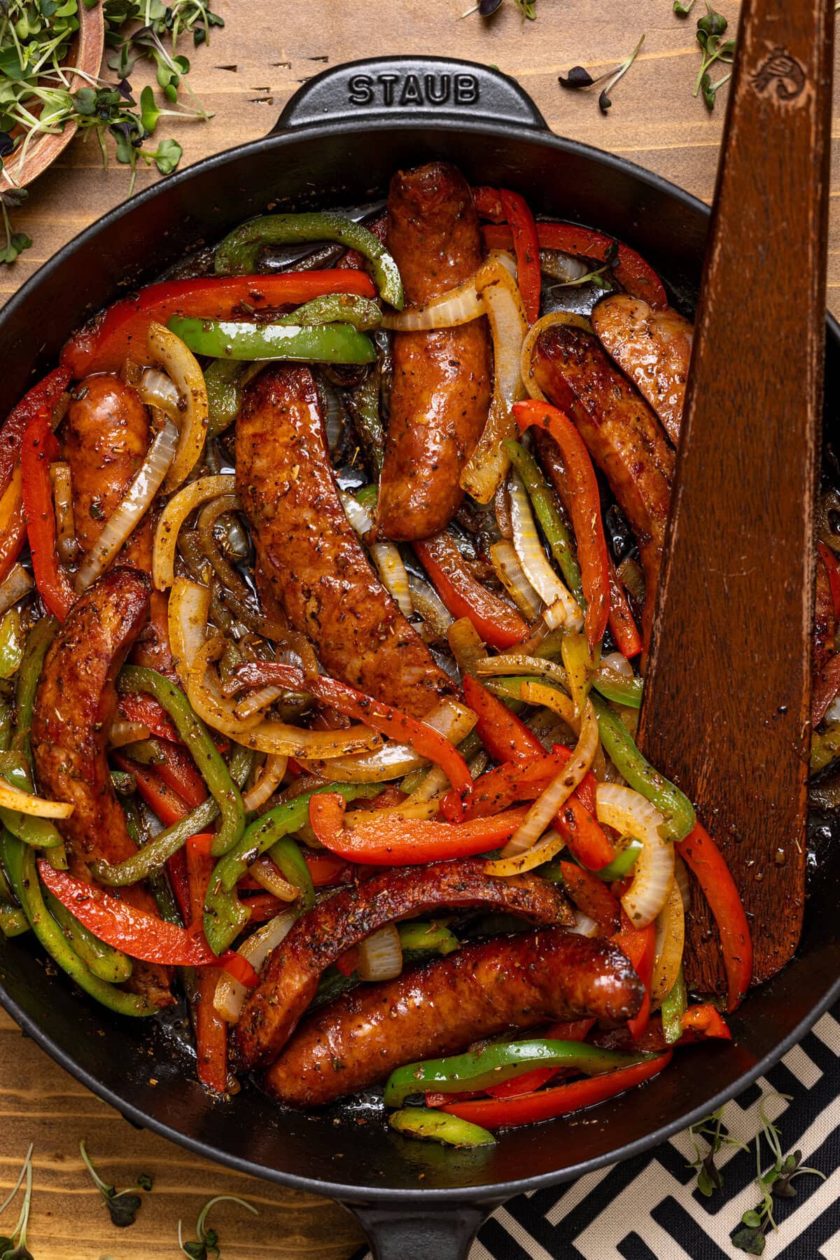 Up close shot of sausage and peppers with a wooden spoon.