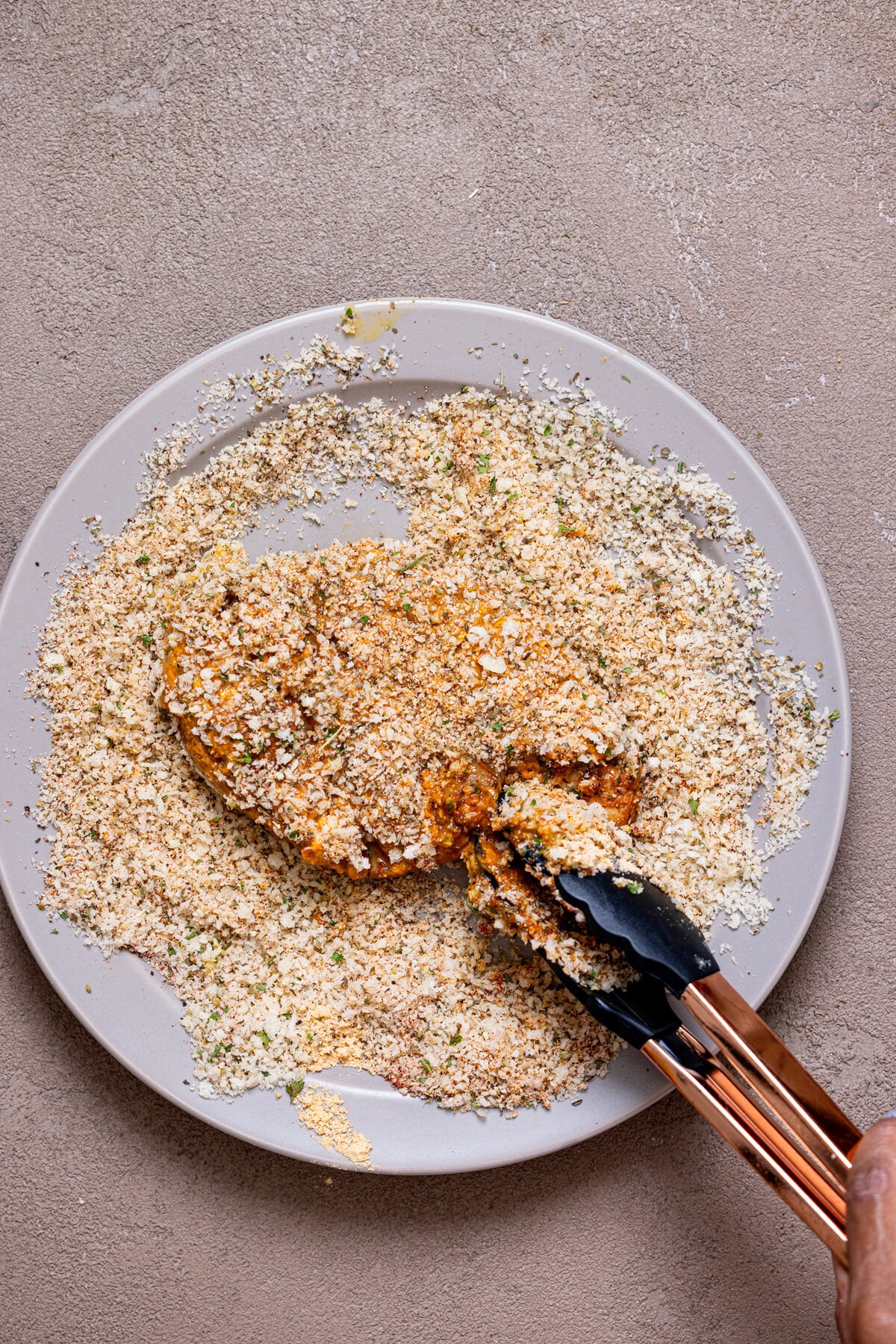 Chicken being tossed in seasoned breadcrumbs. 