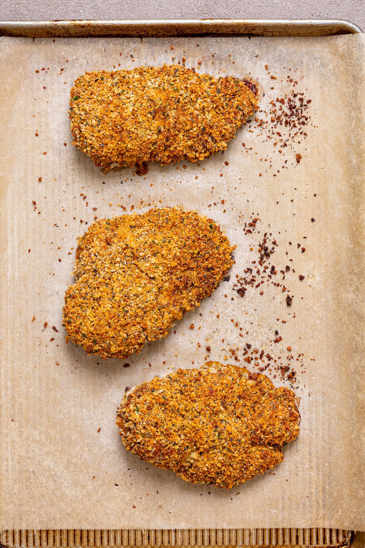 Crispy chicken breasts on a baking sheet with parchment paper.