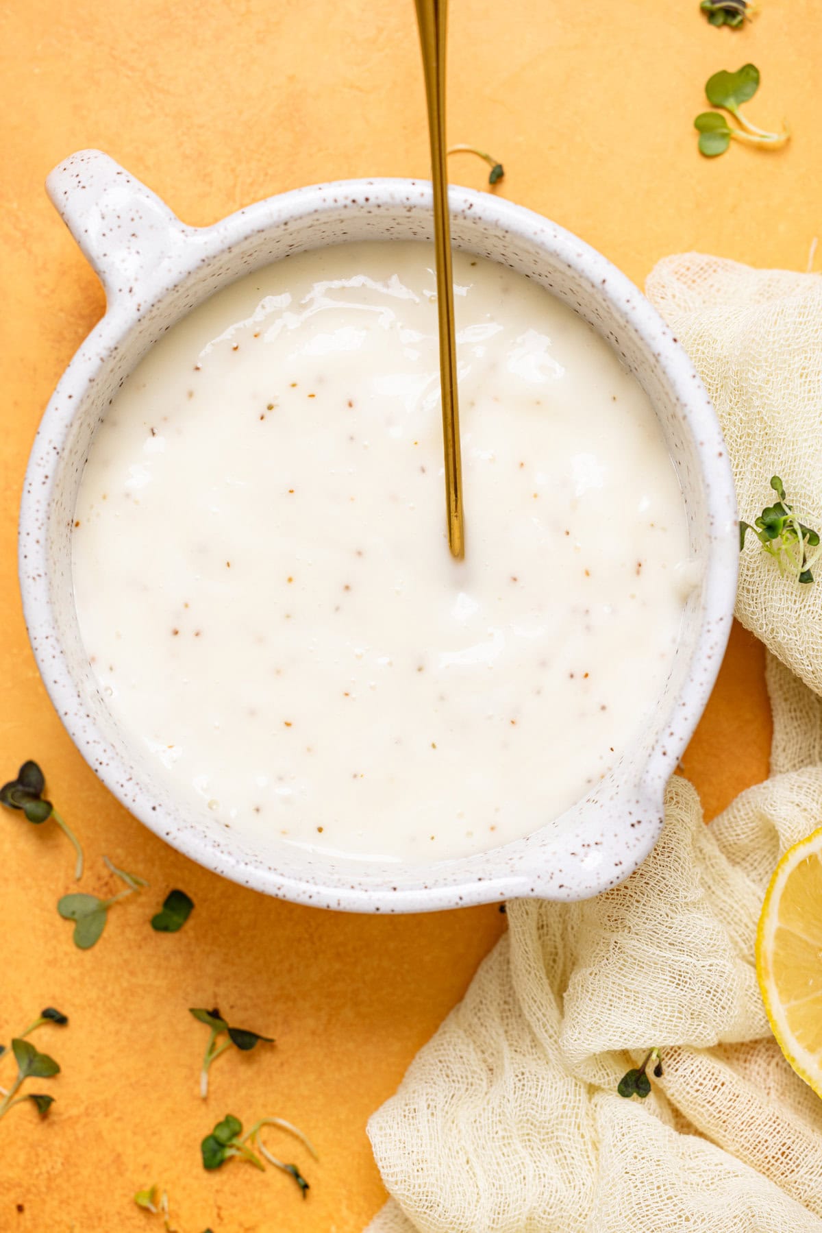 Creamy coleslaw dressing in a bowl with a gold spoon.