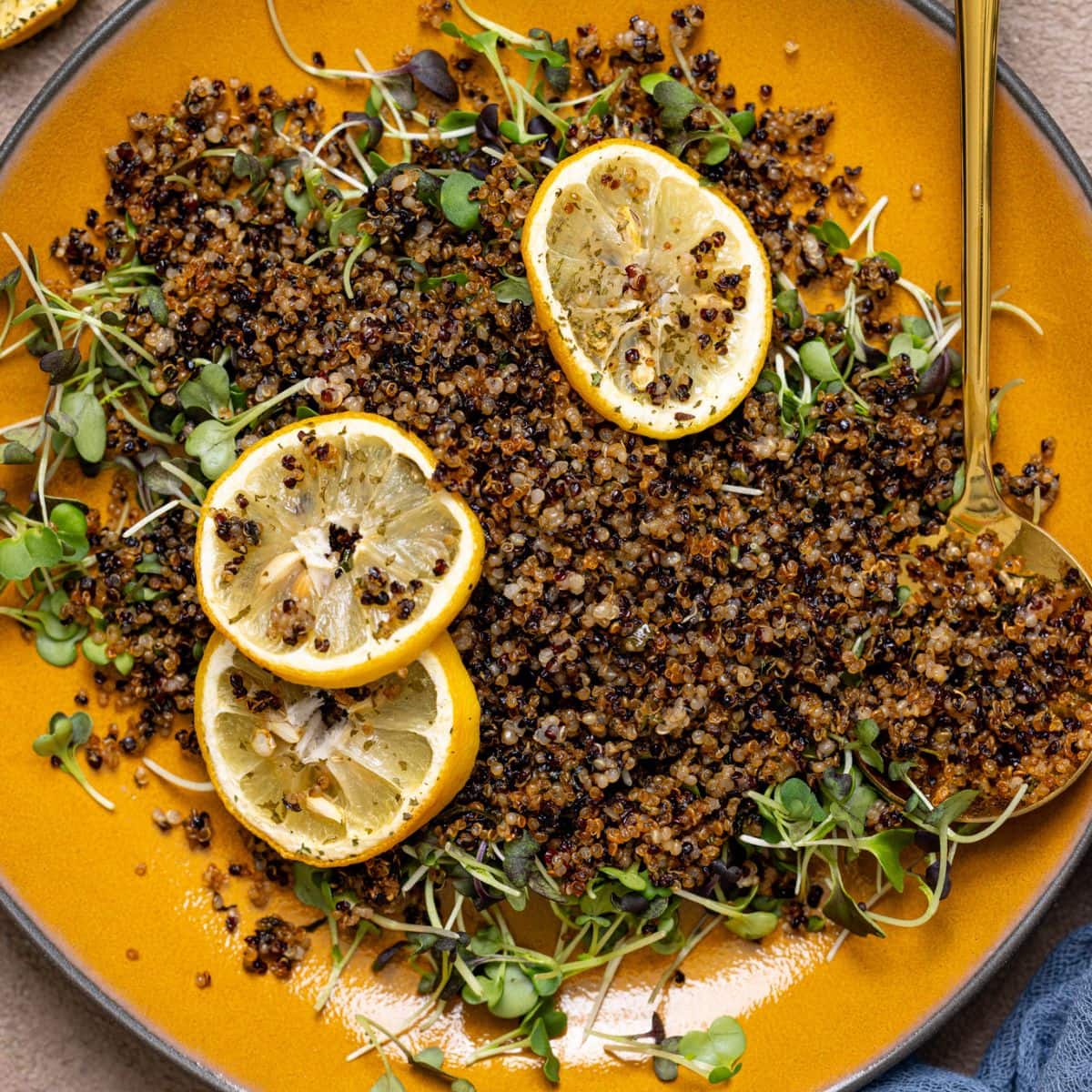 Up close shot of crispy quinoa on a yellow plate with a spoon.