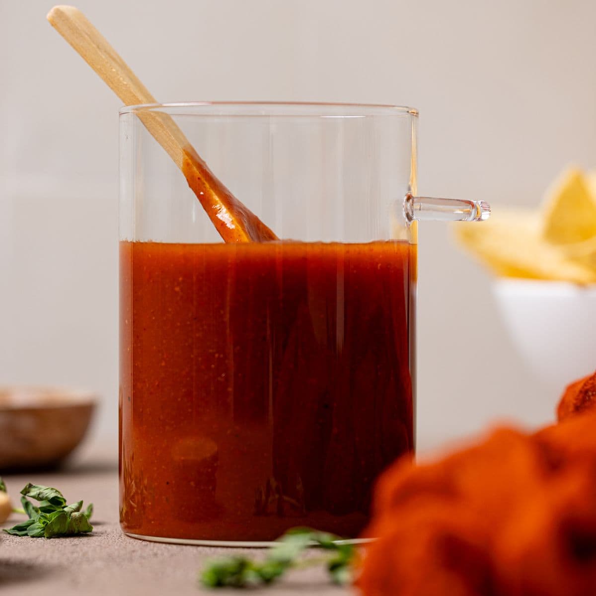 Enchilada sauce in a jar with a wooden spoon.