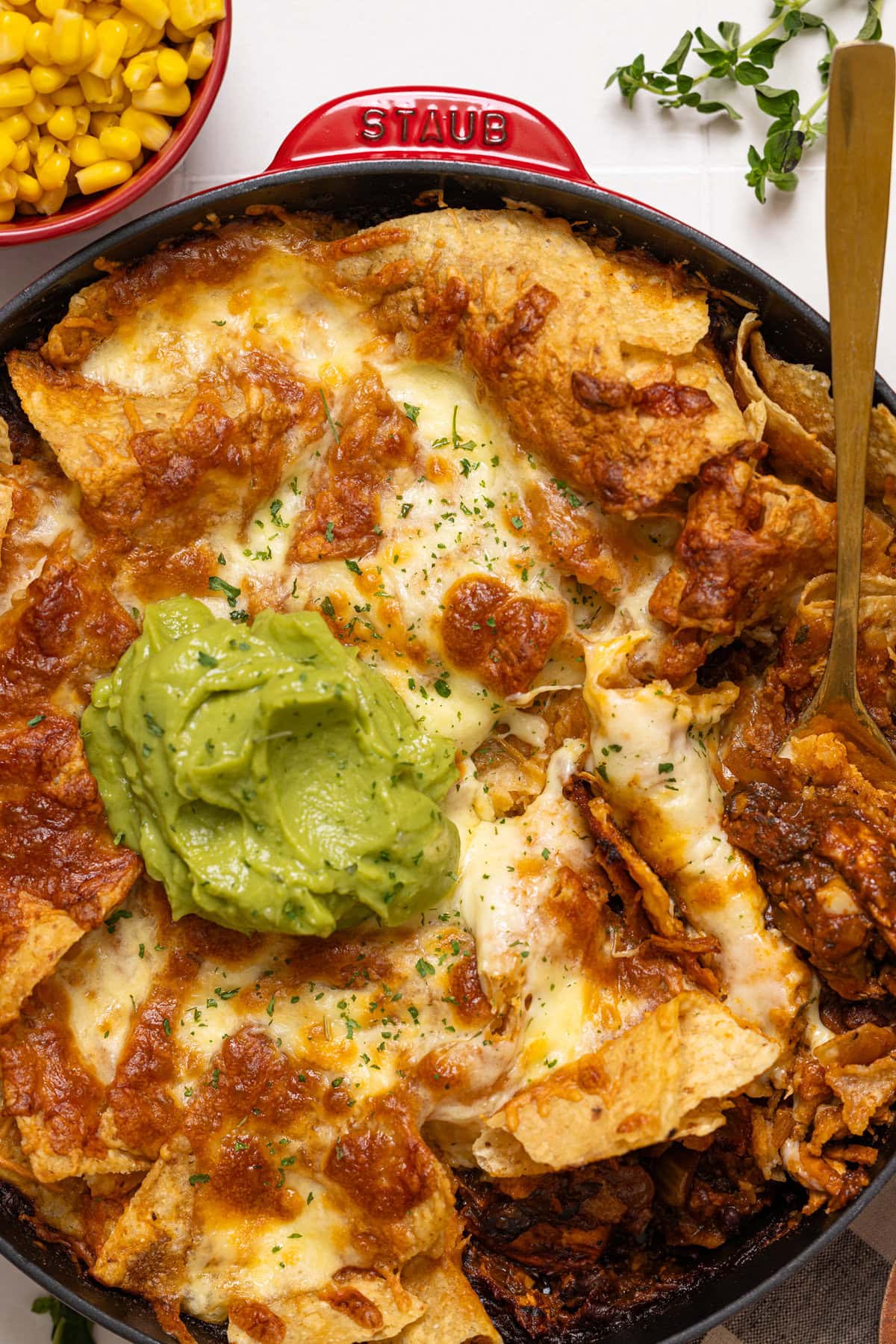 Up close shot of skillet enchiladas with a spoon and toppings.