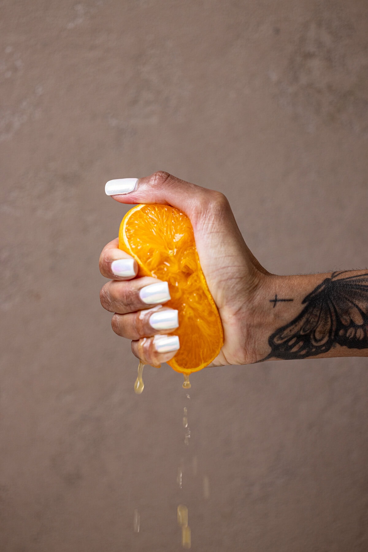 Halved orange being squeezed by a female hand.