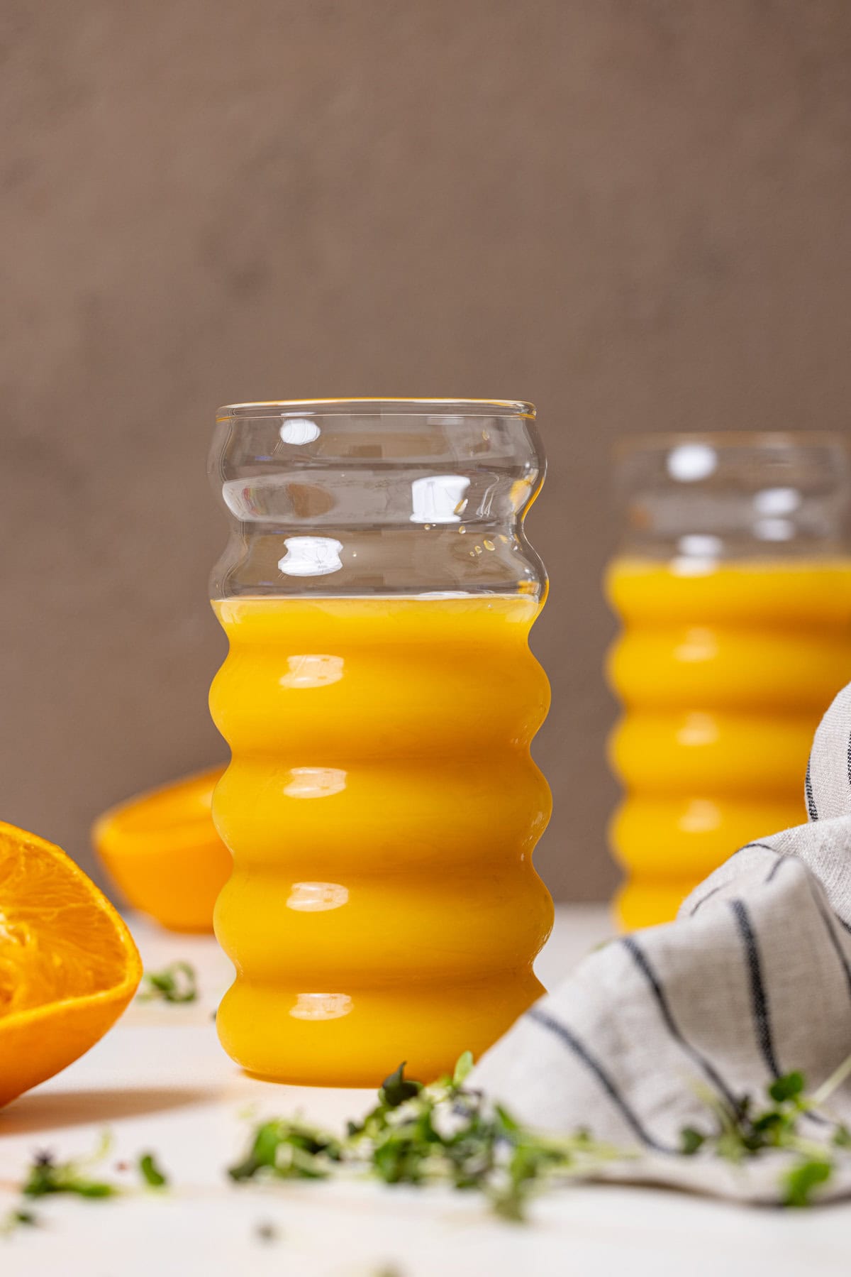 Two glasses of orange juice with sliced oranges.