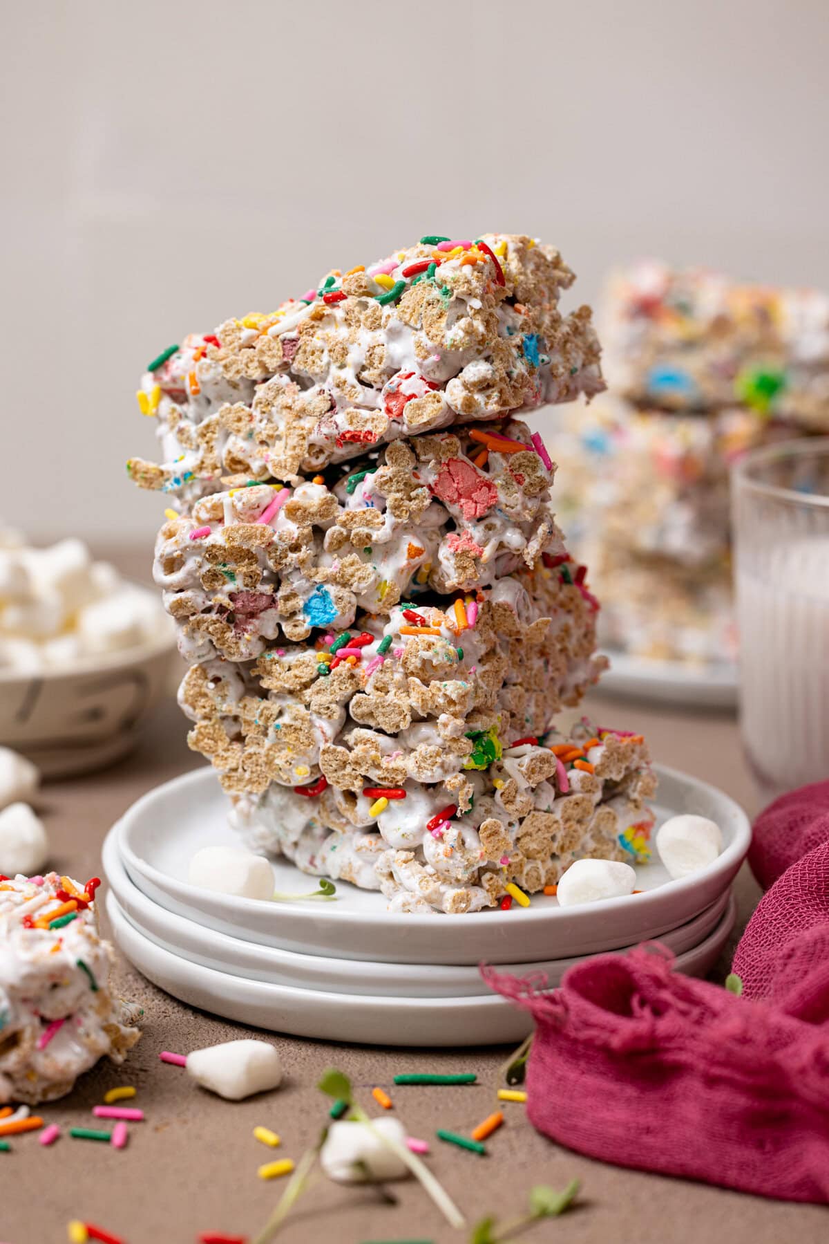 Stacked marshmallow cereal bars on white plates with a glass of milk.