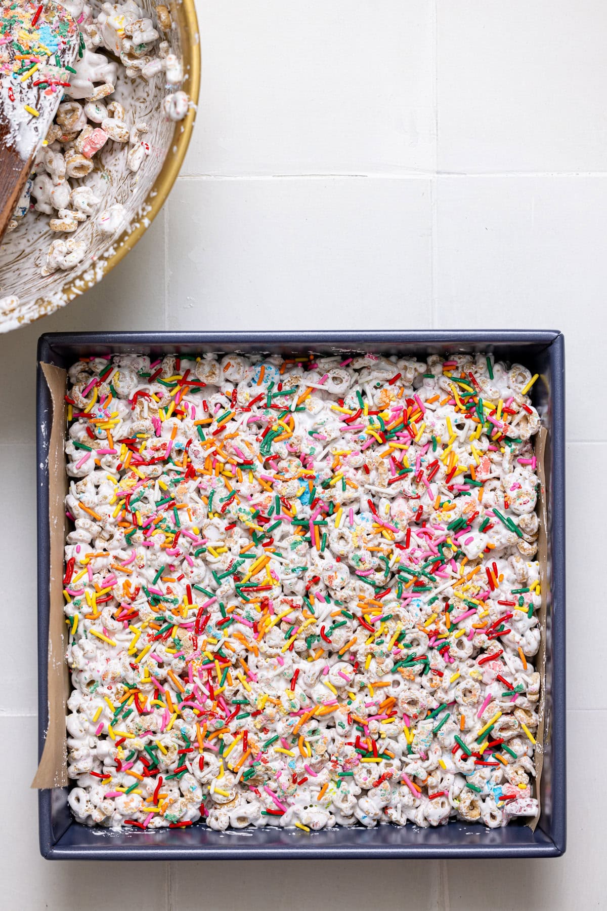 Sprinkles atop cereal bars in a square baking pan.