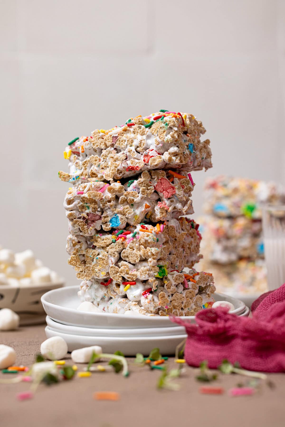 Stacked marshmallow cereal bars on white plates with marshmallows.