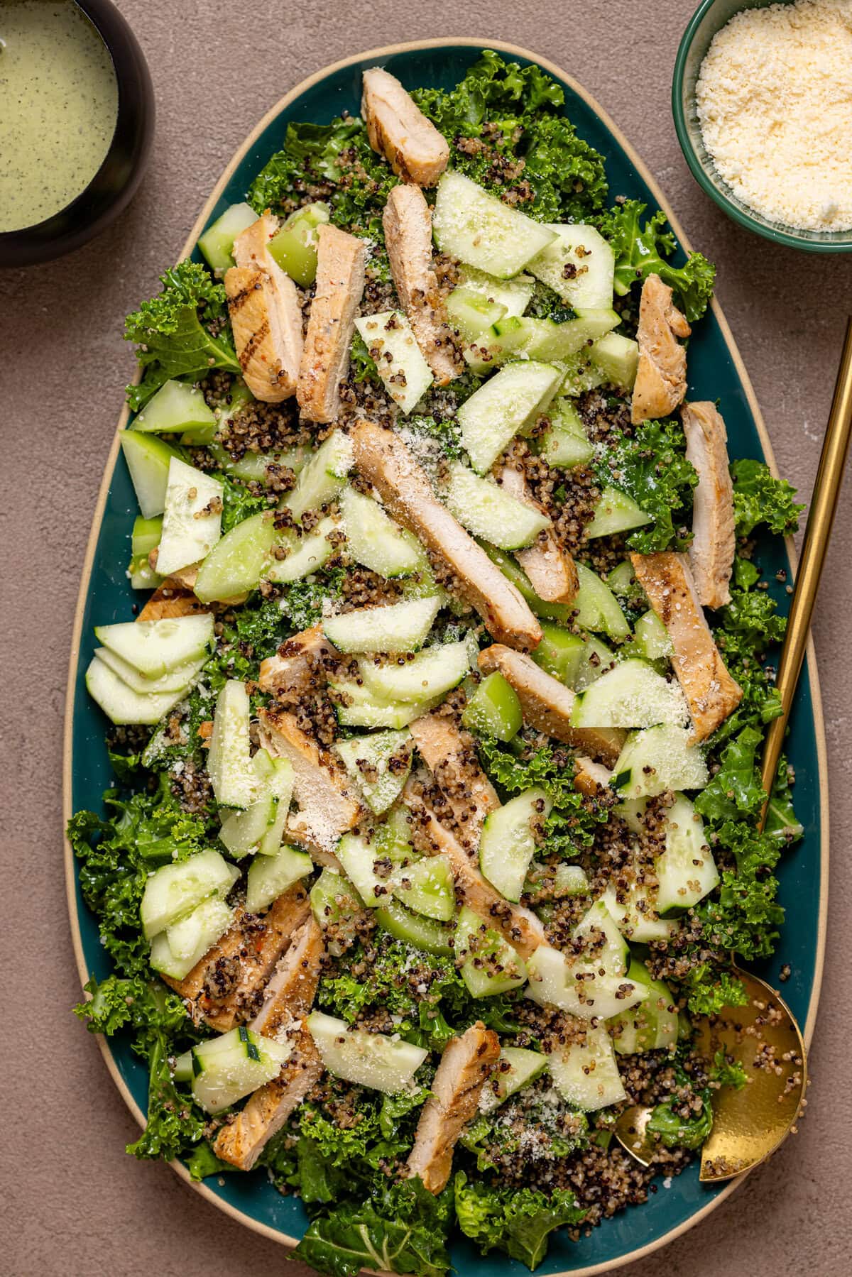 Green goddess chicken salad on a platter with gold serving spoons.