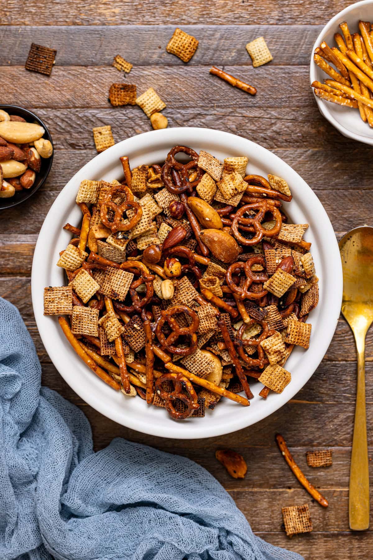 Chex mix in a white bowl with a spoon.