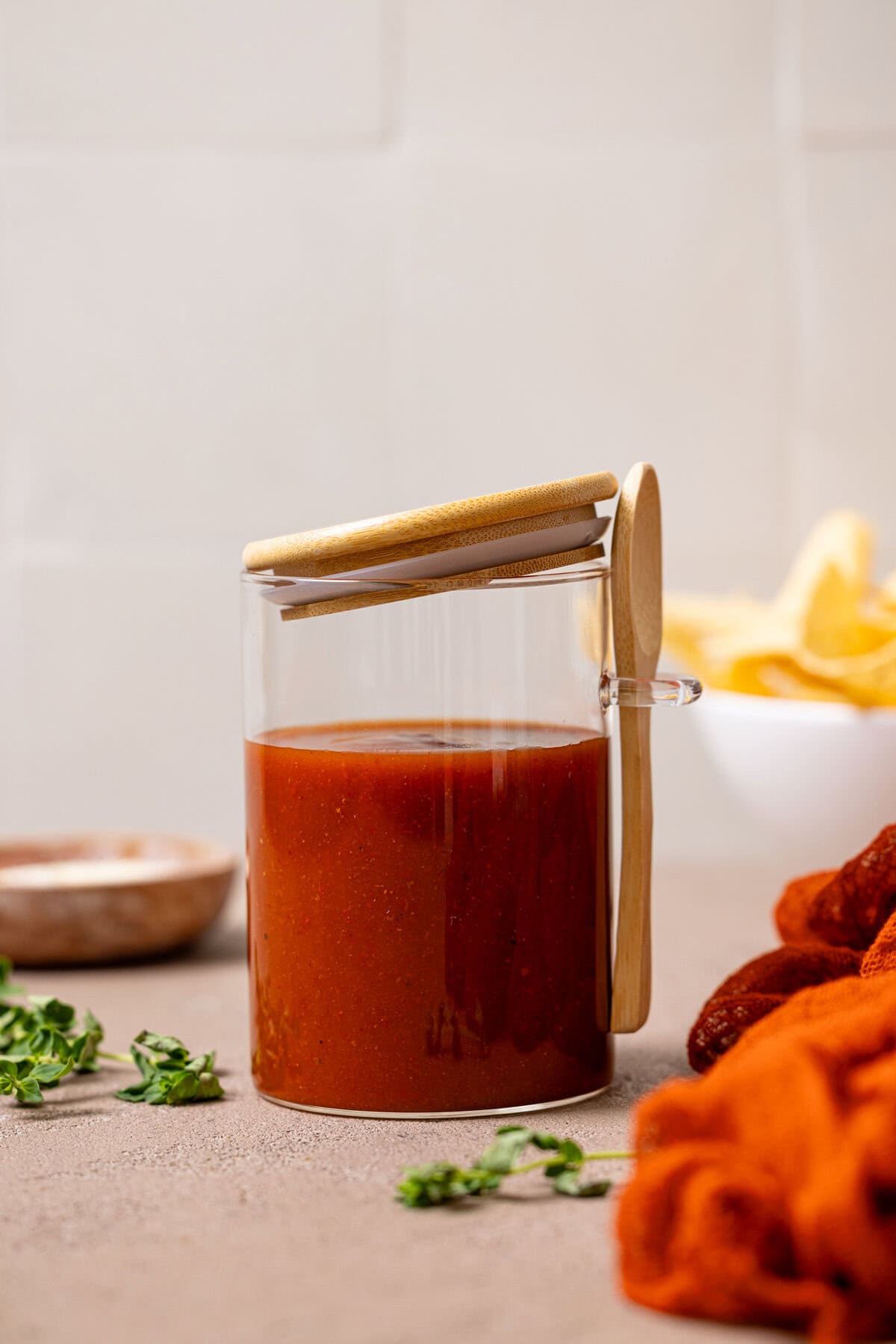 Enchilada sauce in a jar with a red napkin and tortilla chips in the background.