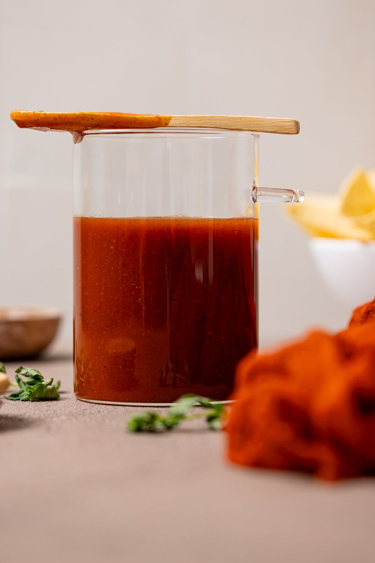 Enchilada sauce in a jar with a spoon sitting at the top of jar.