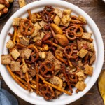 Chex mix in a white bowl with a spoon.