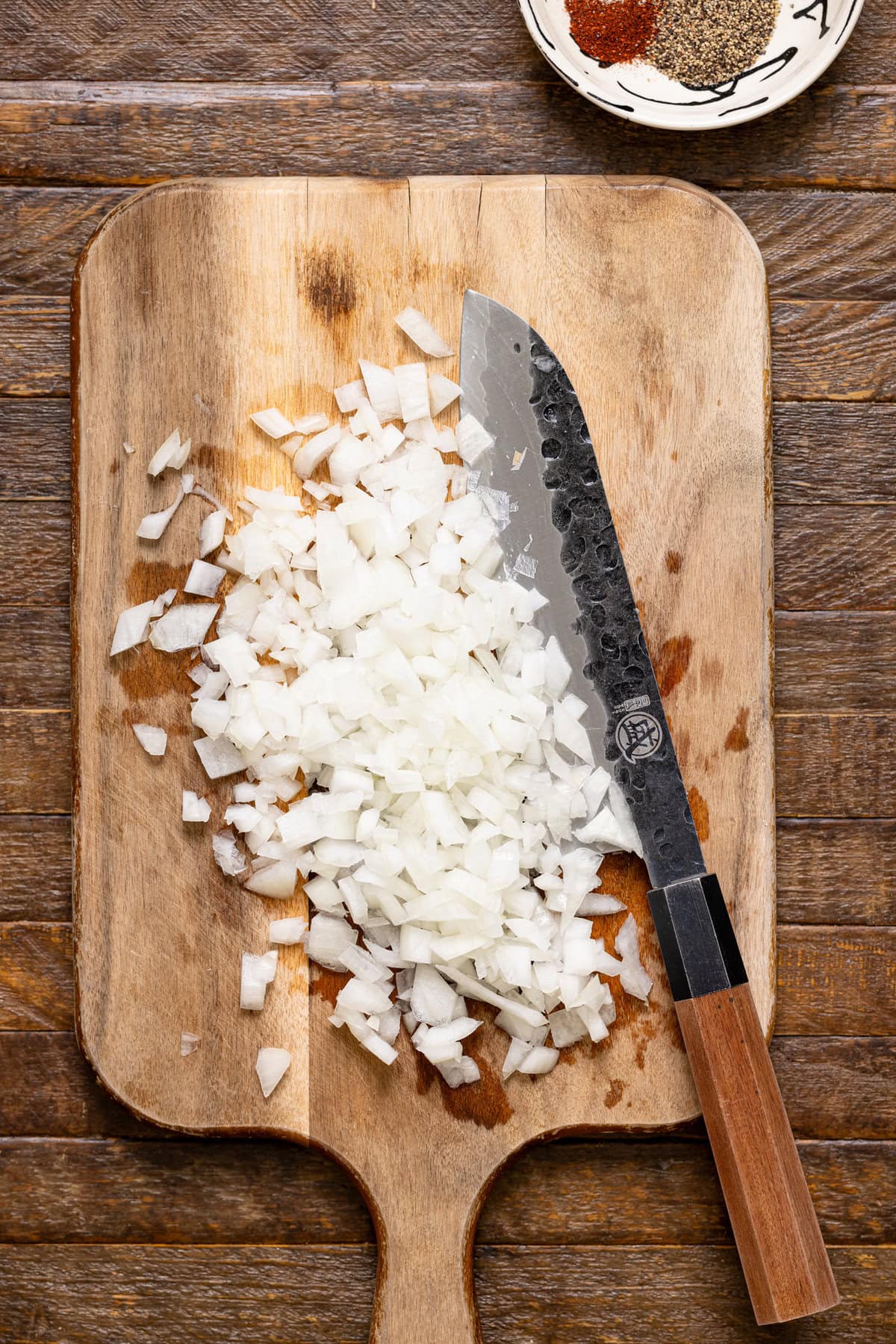 Chopped onions on a cutting board with a knife.