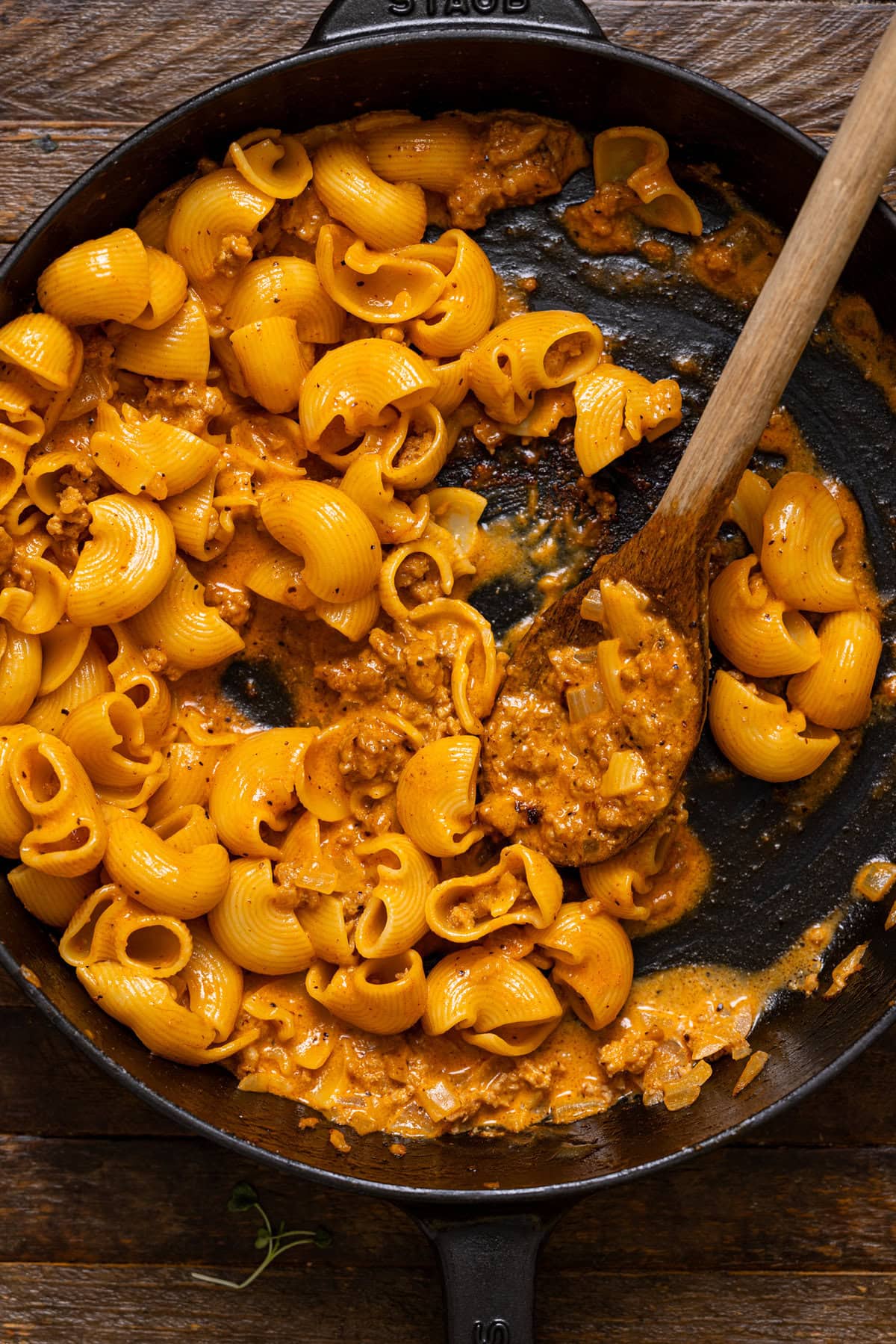 Hamburger Helper in a black skillet with a wooden spoon.