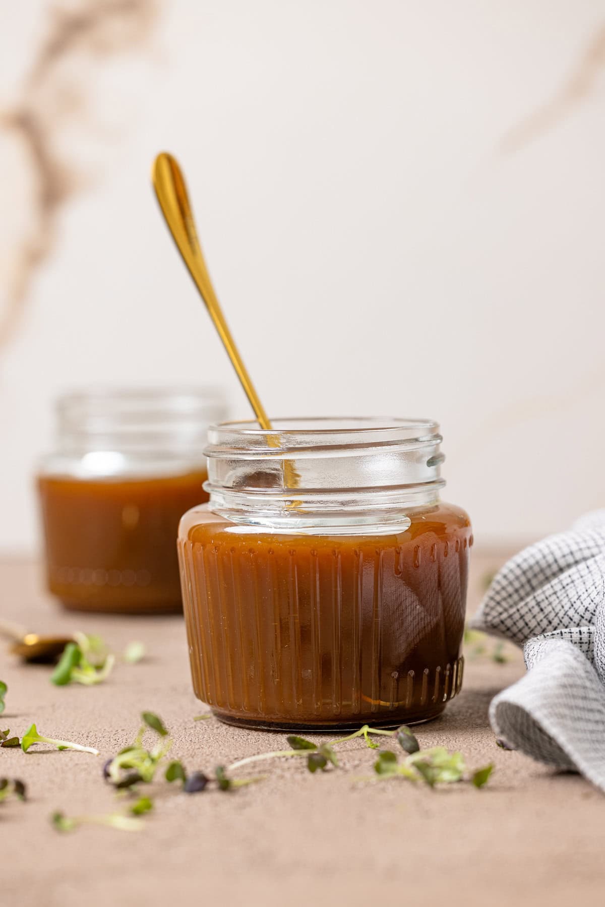 Caramel sauce in two mason jars with a spoon.