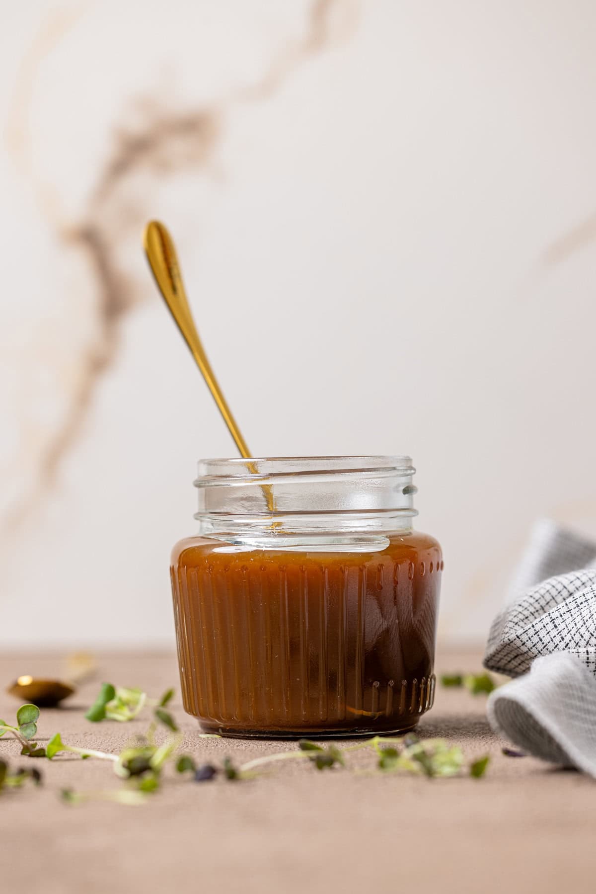 Caramel sauce in a mason jar with a spoon.