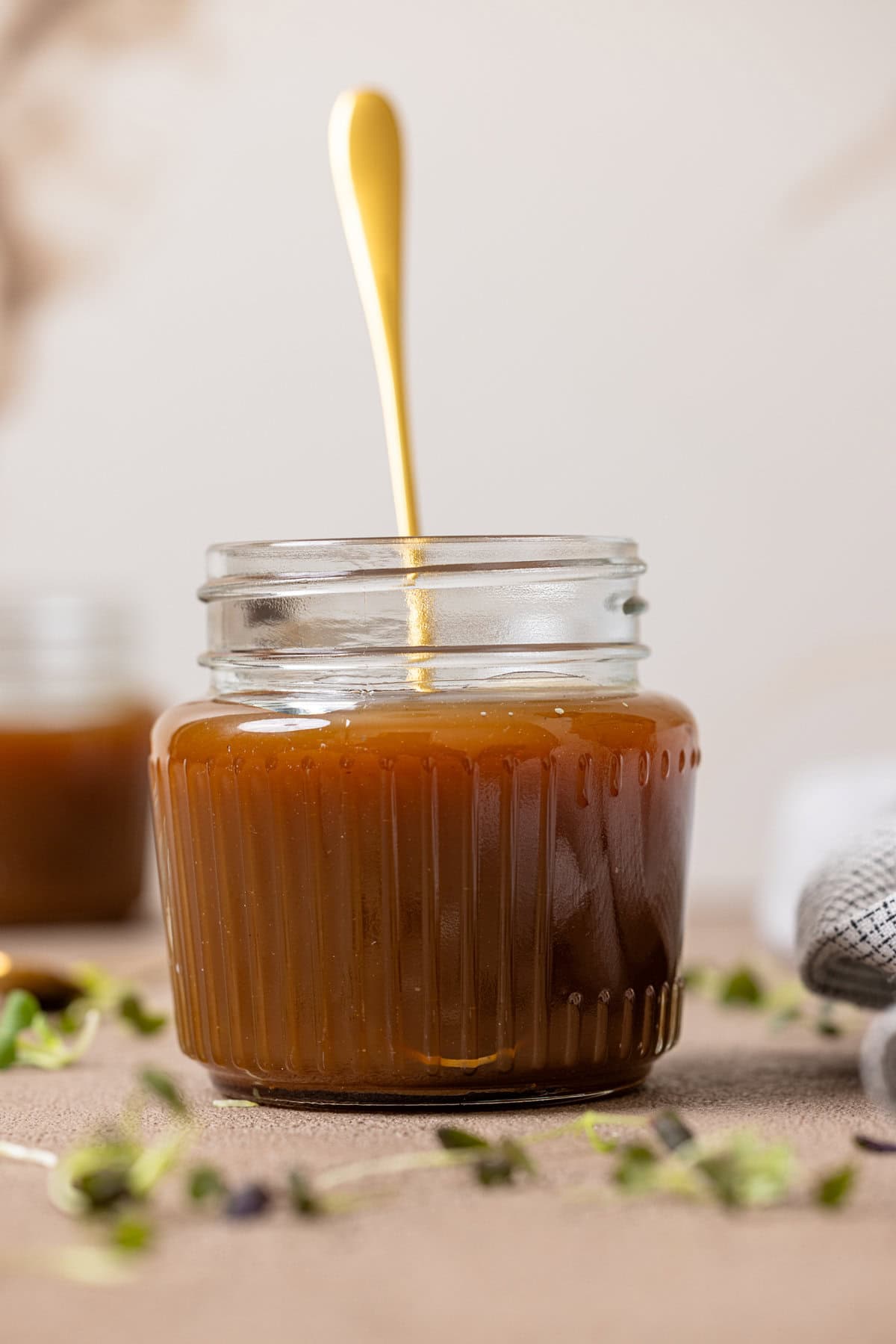 Up close shot of caramel sauce in a mason jar with a spoon.