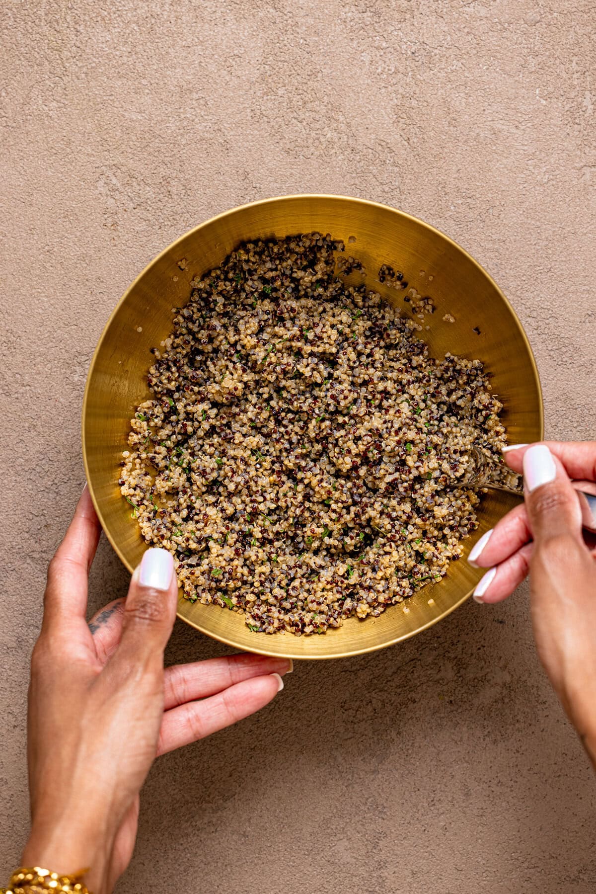 Ingredients in a gold bowl being stirred with a spoon.