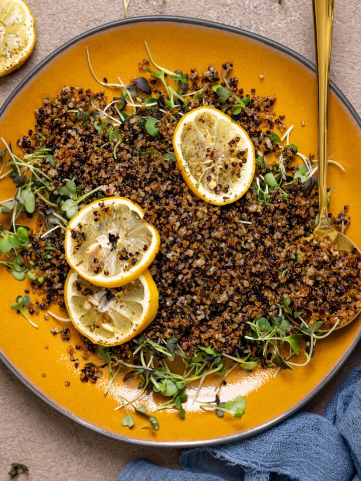 Up close shot of crispy quinoa on a yellow plate with a spoon.