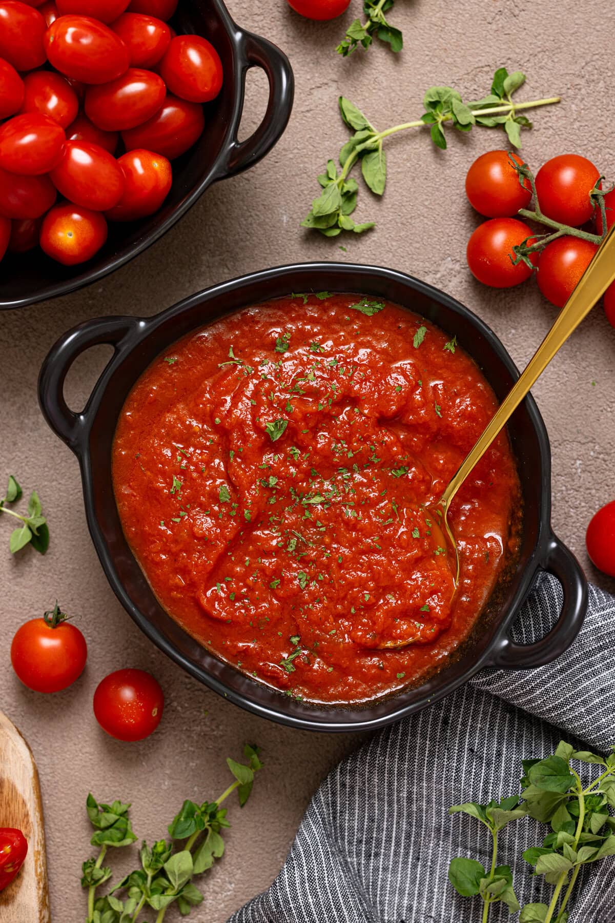 Tomato sauce in a black bowl with a spoon.