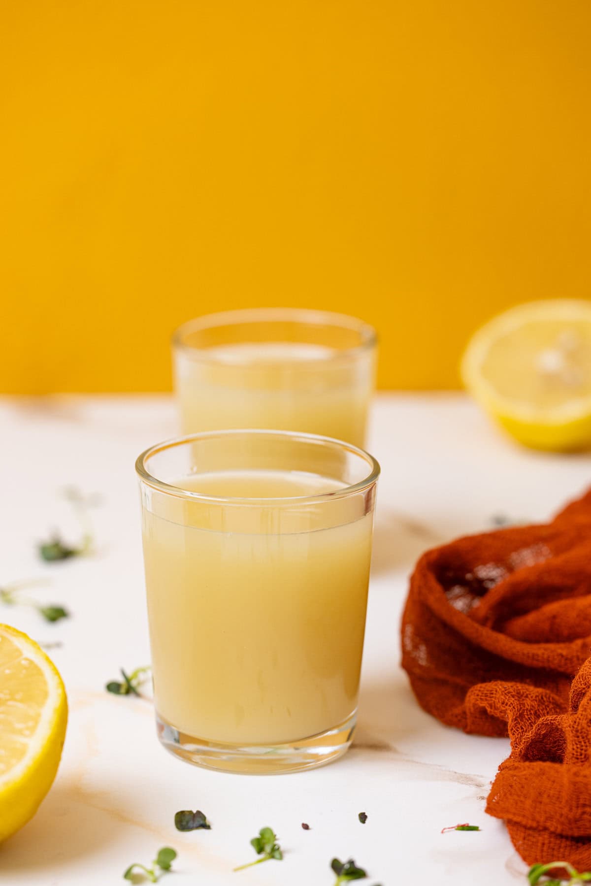 Two glasses of lemon juice on a white table.