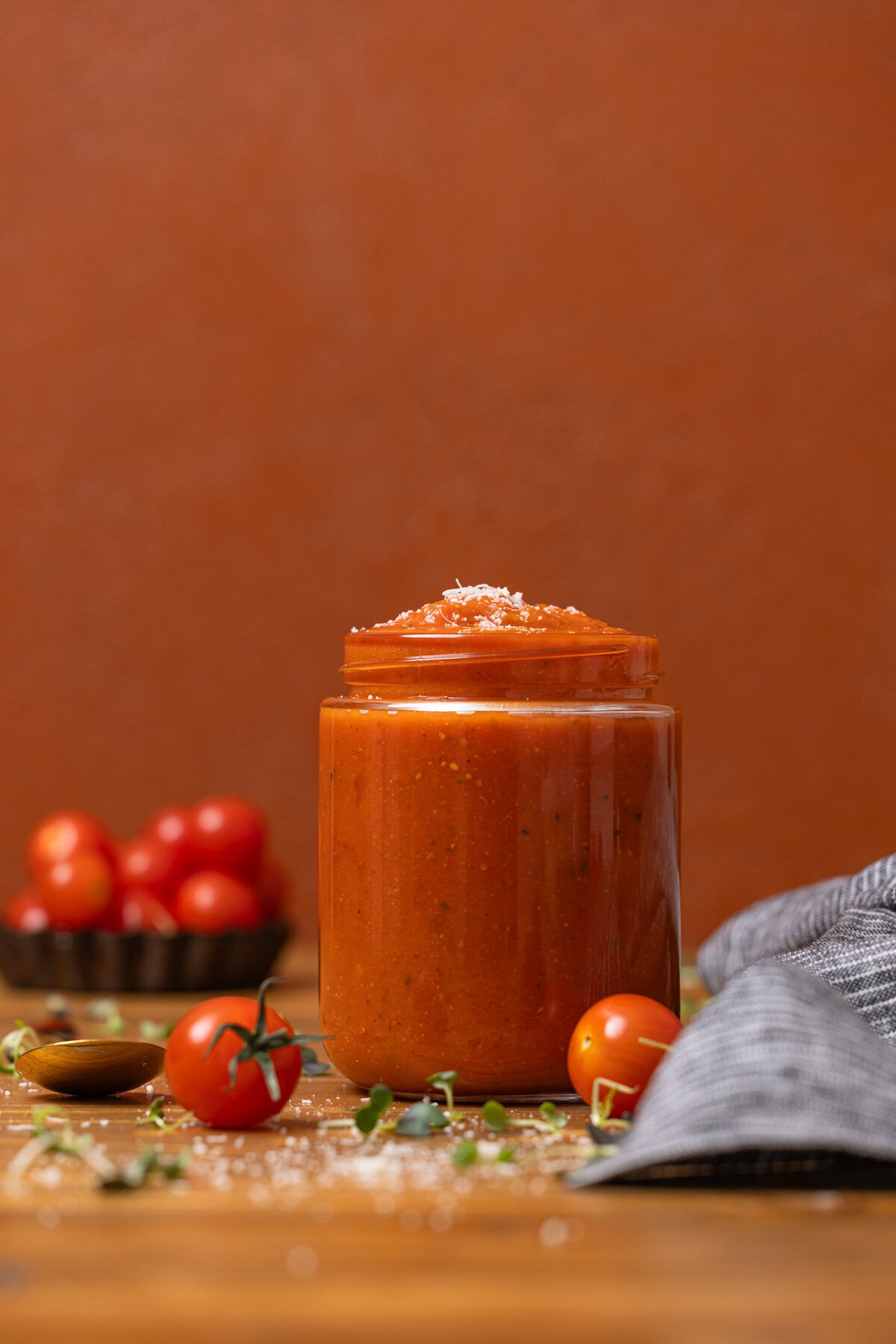 Vodka sauce in a jar with tomatoes in the background.