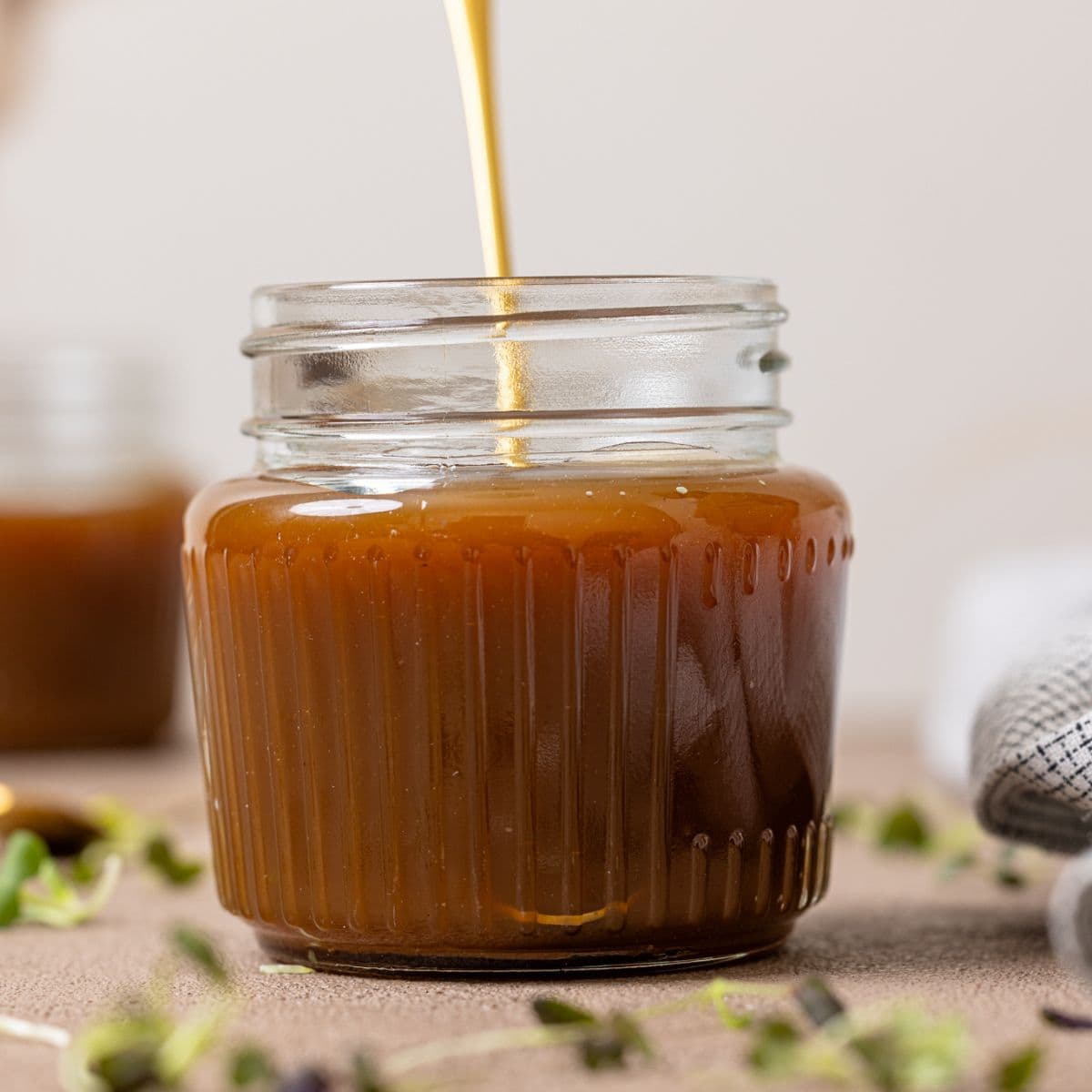 Up close shot of caramel sauce in a mason jar with a spoon.