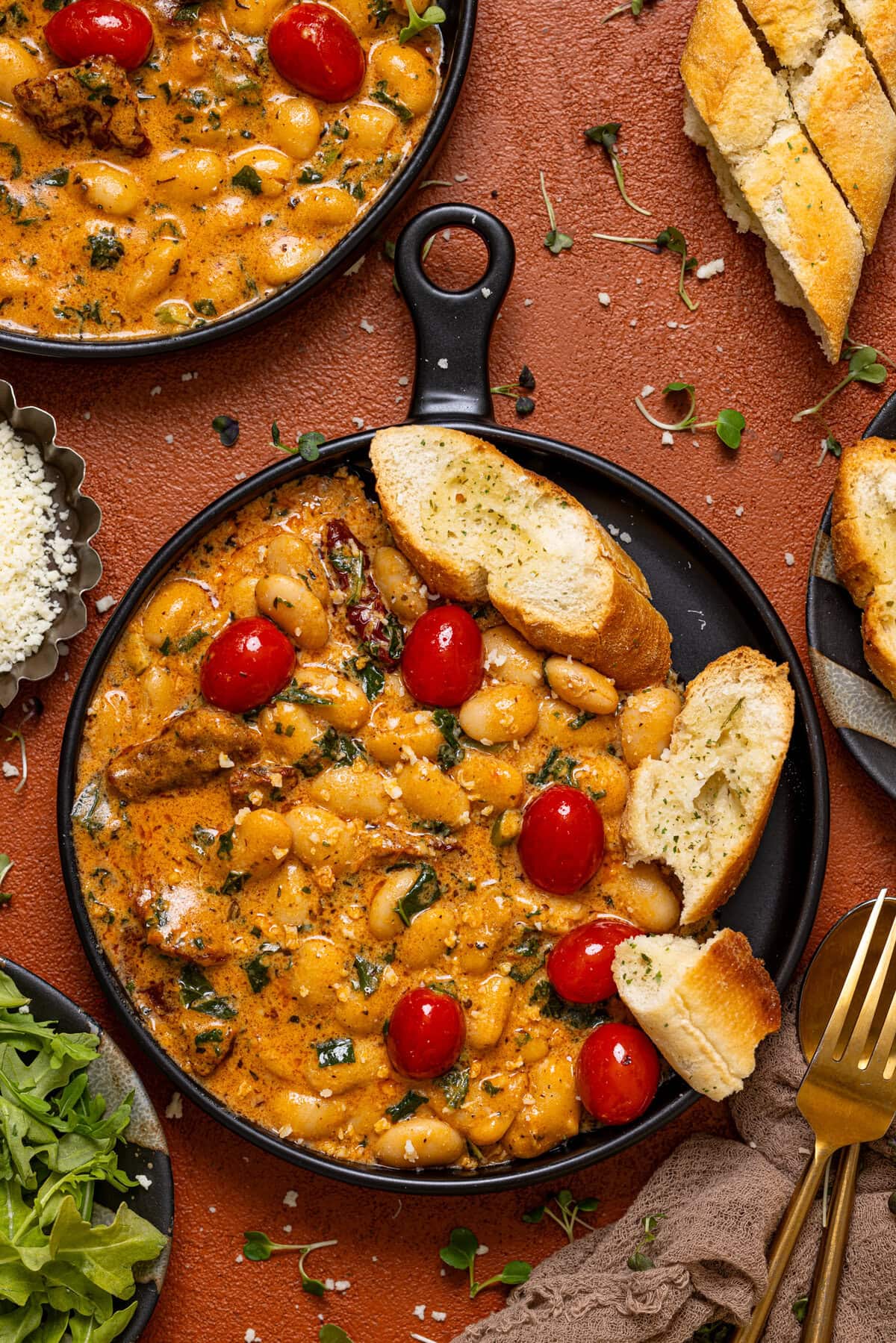 Marry Me beans in two black plates with a fork, bread, and greens.