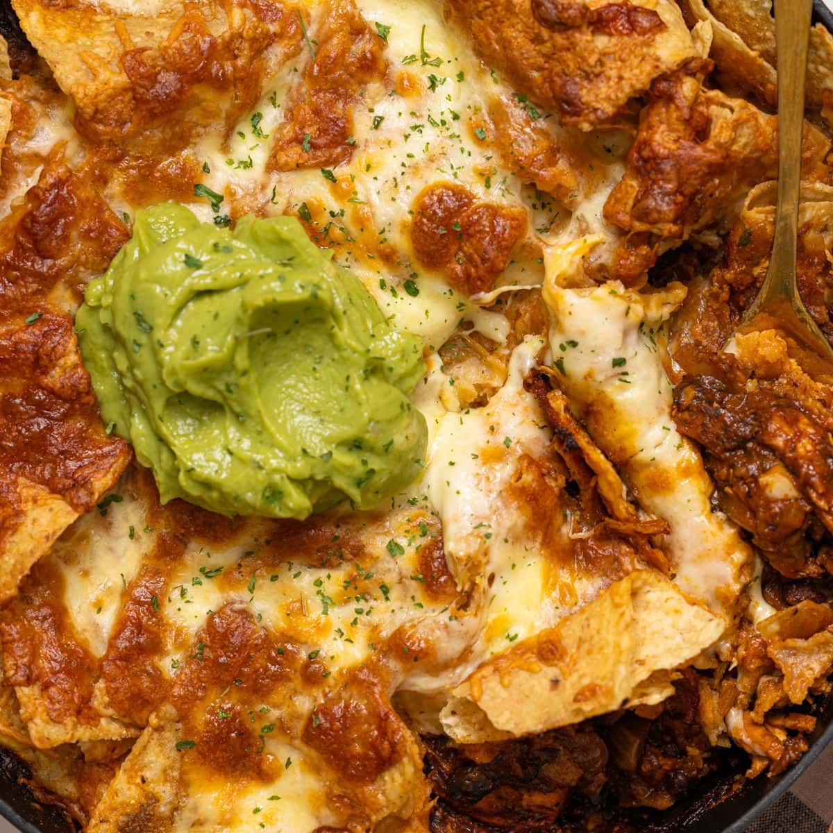 Baked enchilada in a skillet with guacamole.