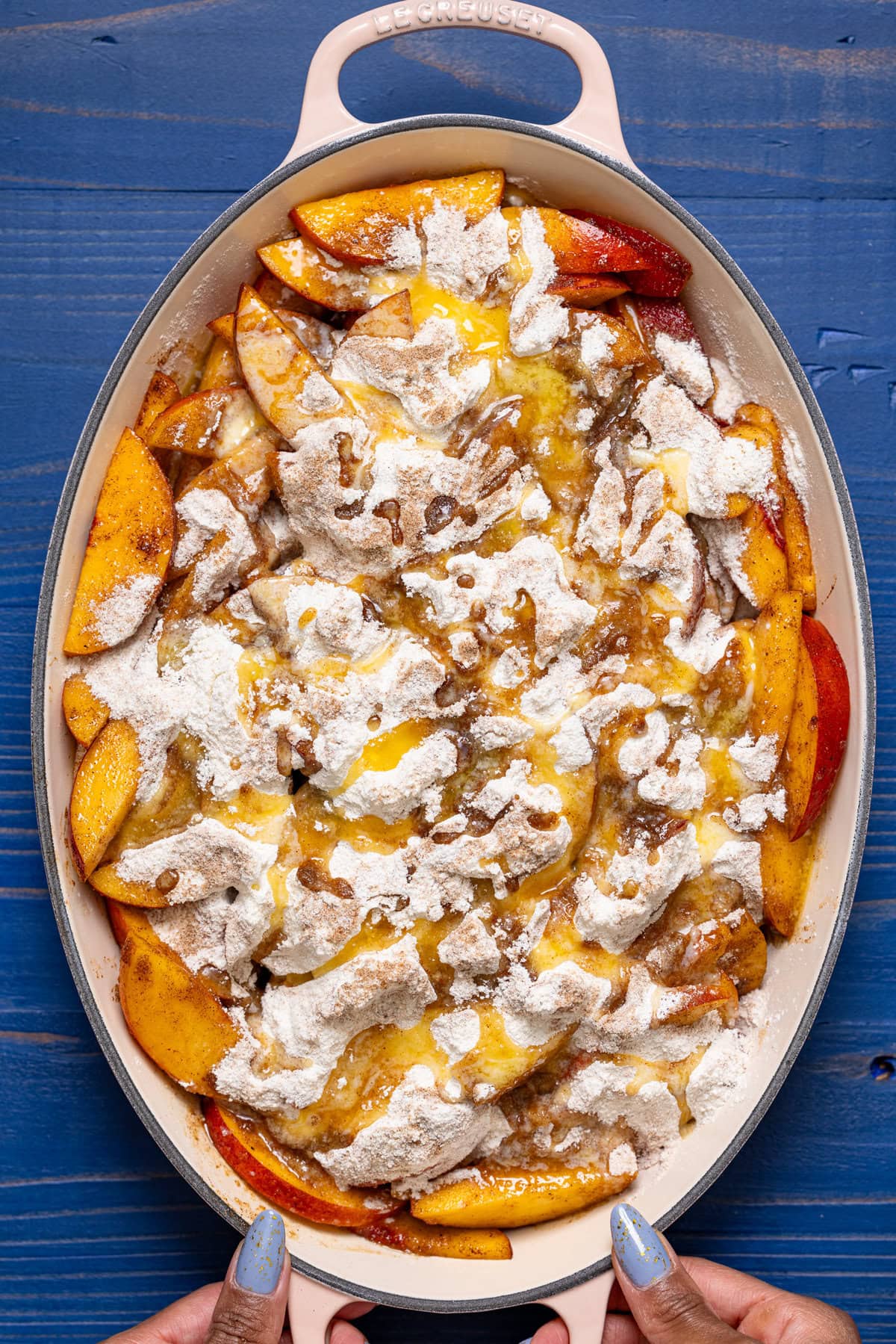 Layered dump cake ingredients in a baking dish being held.