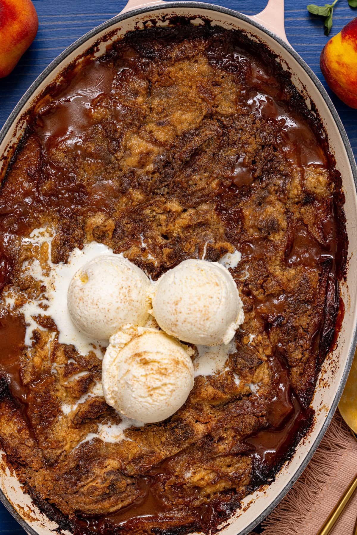 Baked peach dump cake in a baking dish with scoops of ice cream on top.