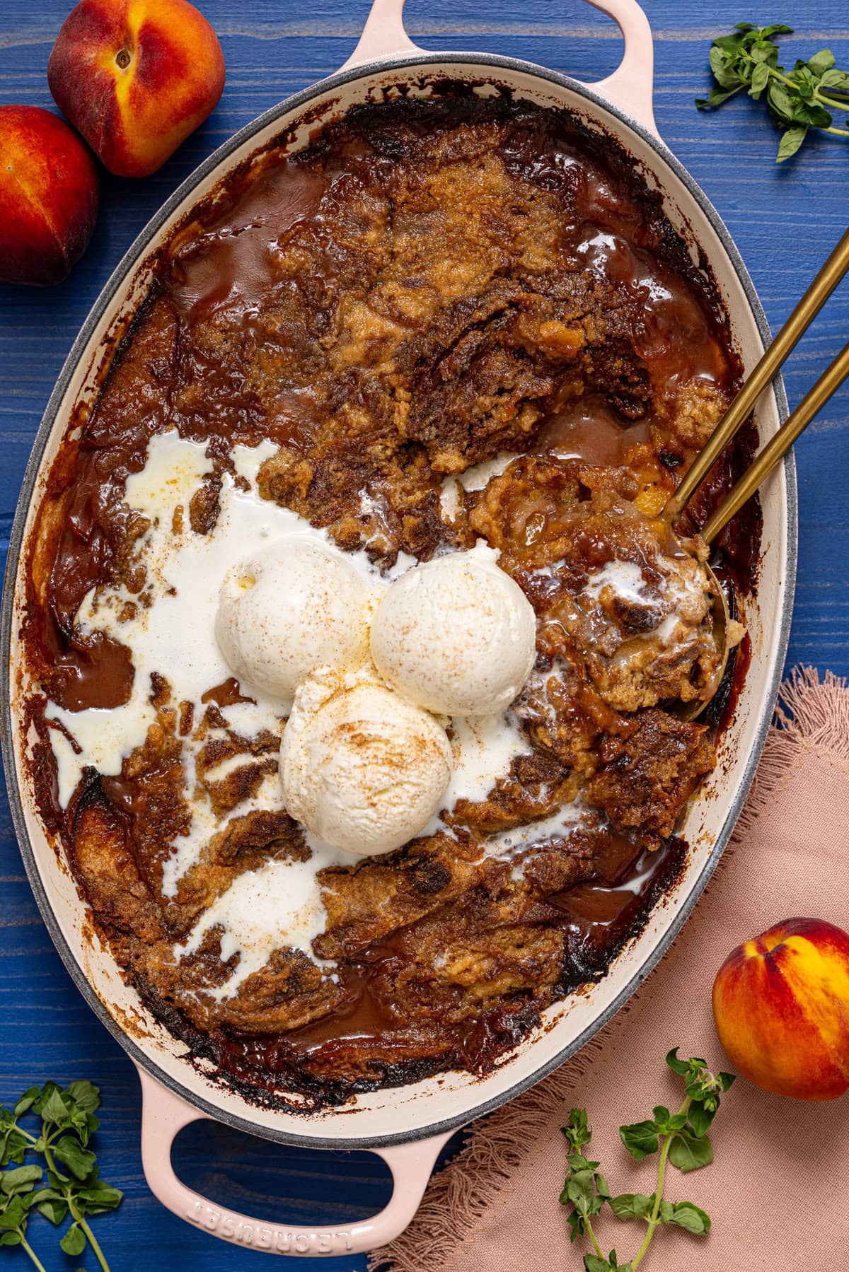 Baked peach dump cake being scooped with a spoon in a baking dish with peaches.