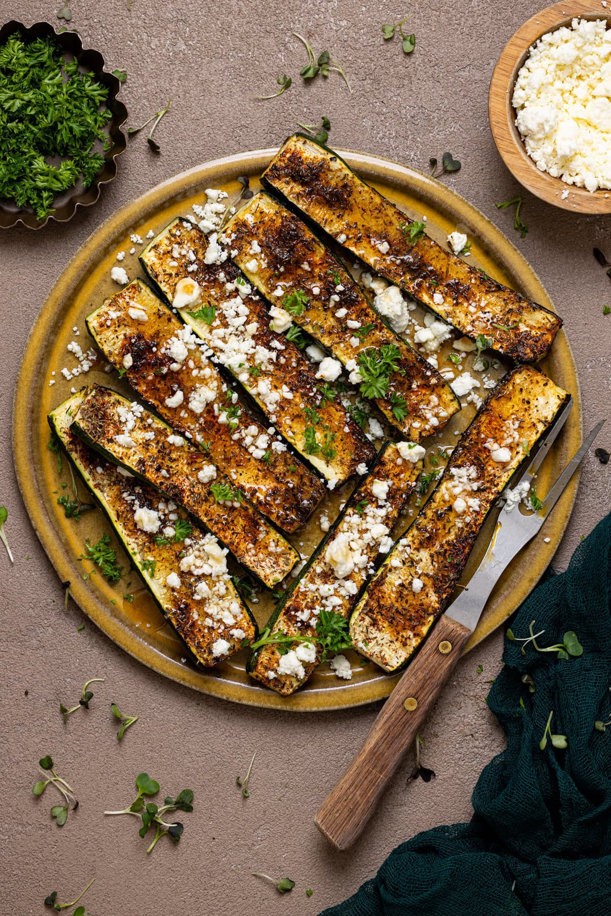 Roasted zucchini on a  plate with a fork and garnish.