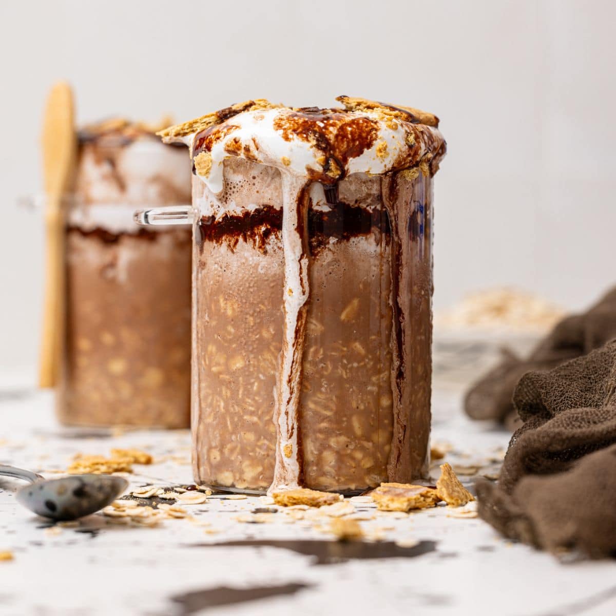 Two jars filled with S'more overnight oats with a spoon and Graham crackers as topping.