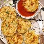 Fried green tomato on a plate, dipped in red sauce, and with a fork.