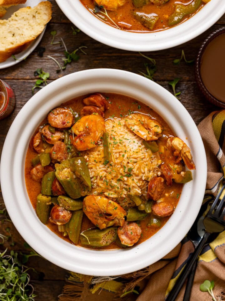 Up close shot of two bowls of gumbo with a fork + spoon.