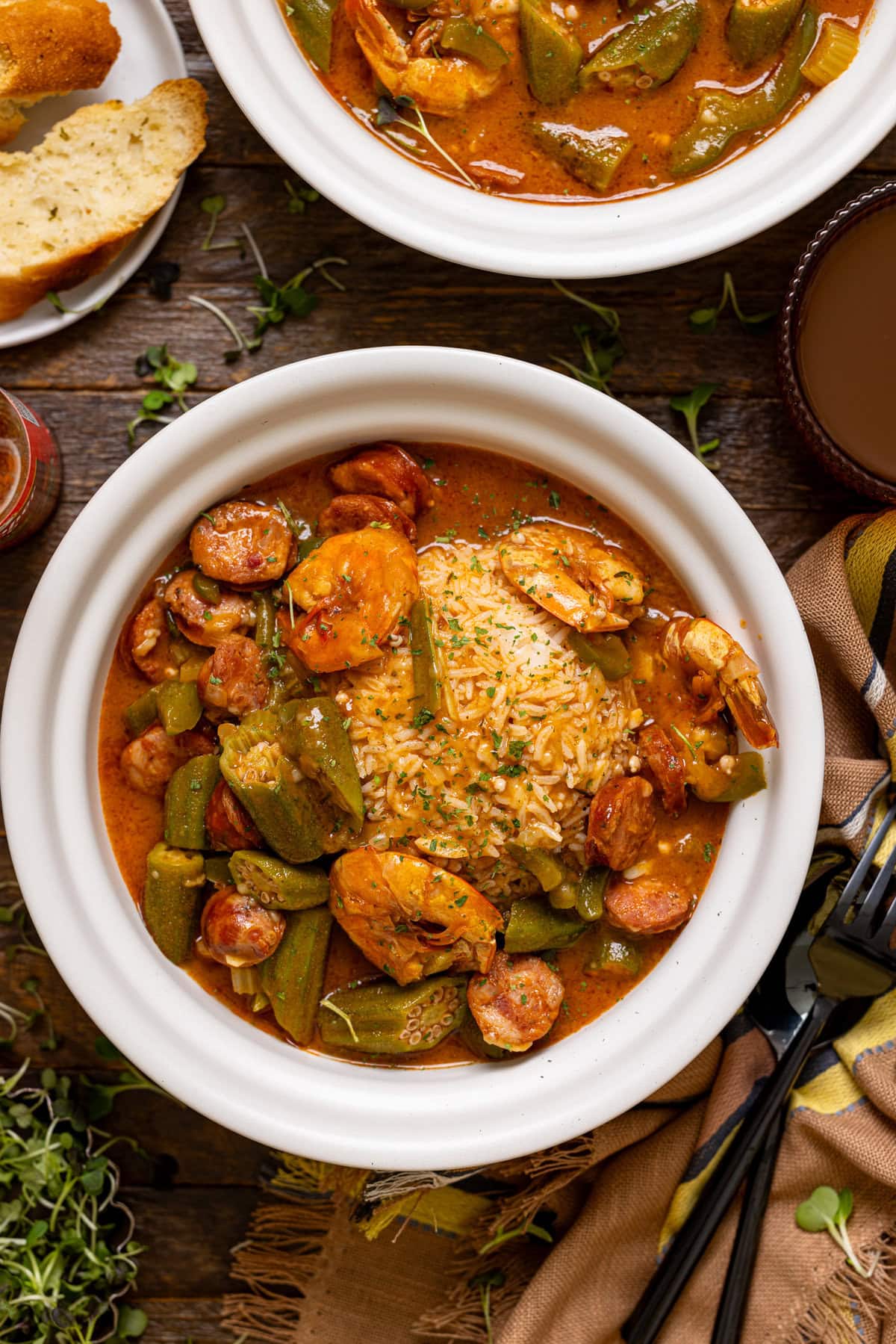 Up close shot of two bowls of gumbo with a fork + spoon.