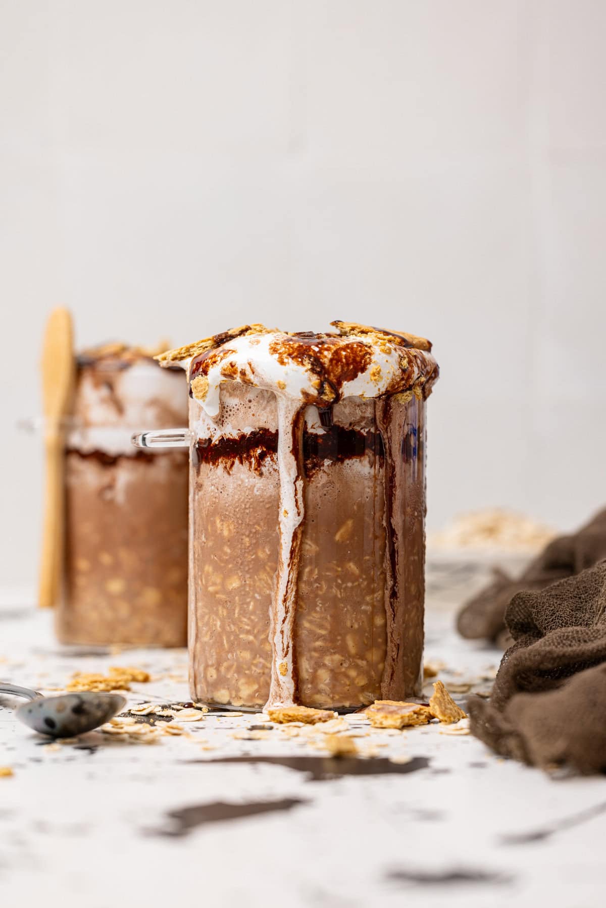 Two jars filled with S'more overnight oats with a spoon and Graham crackers as topping.