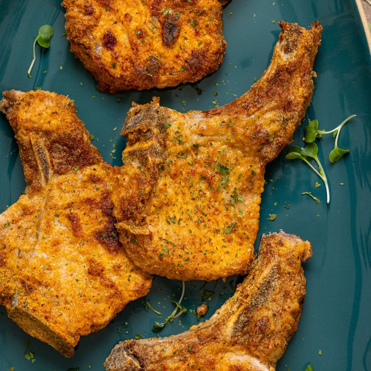 Up close shot of air fried pork chops on a blue platter.