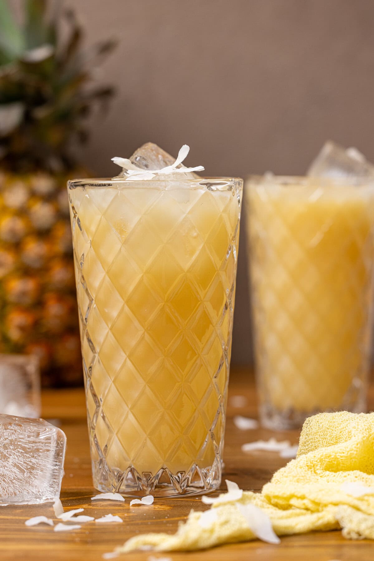 Two glasses of pineapple coconut drink with a pineapple in the background.