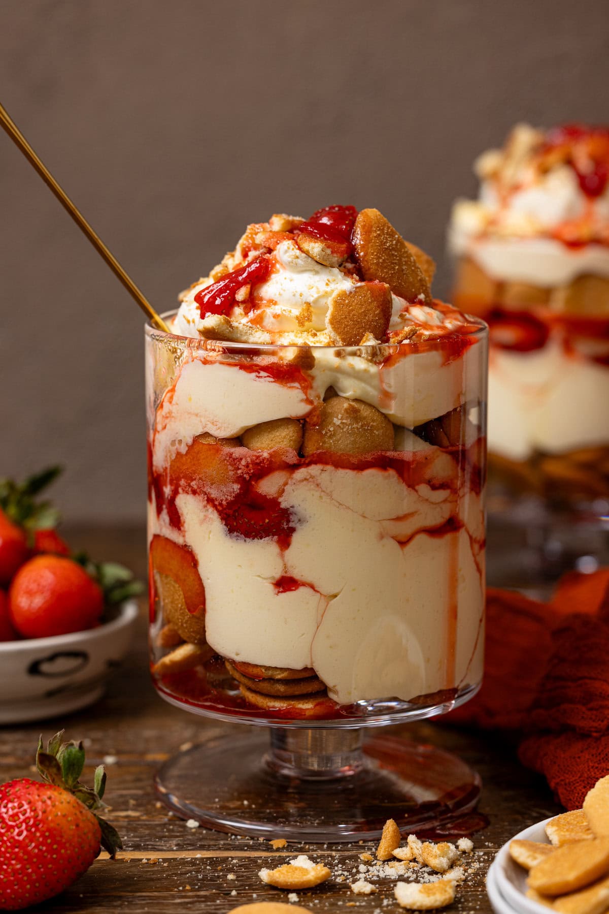 Two trifle bowls of strawberry banana pudding with a spoon.