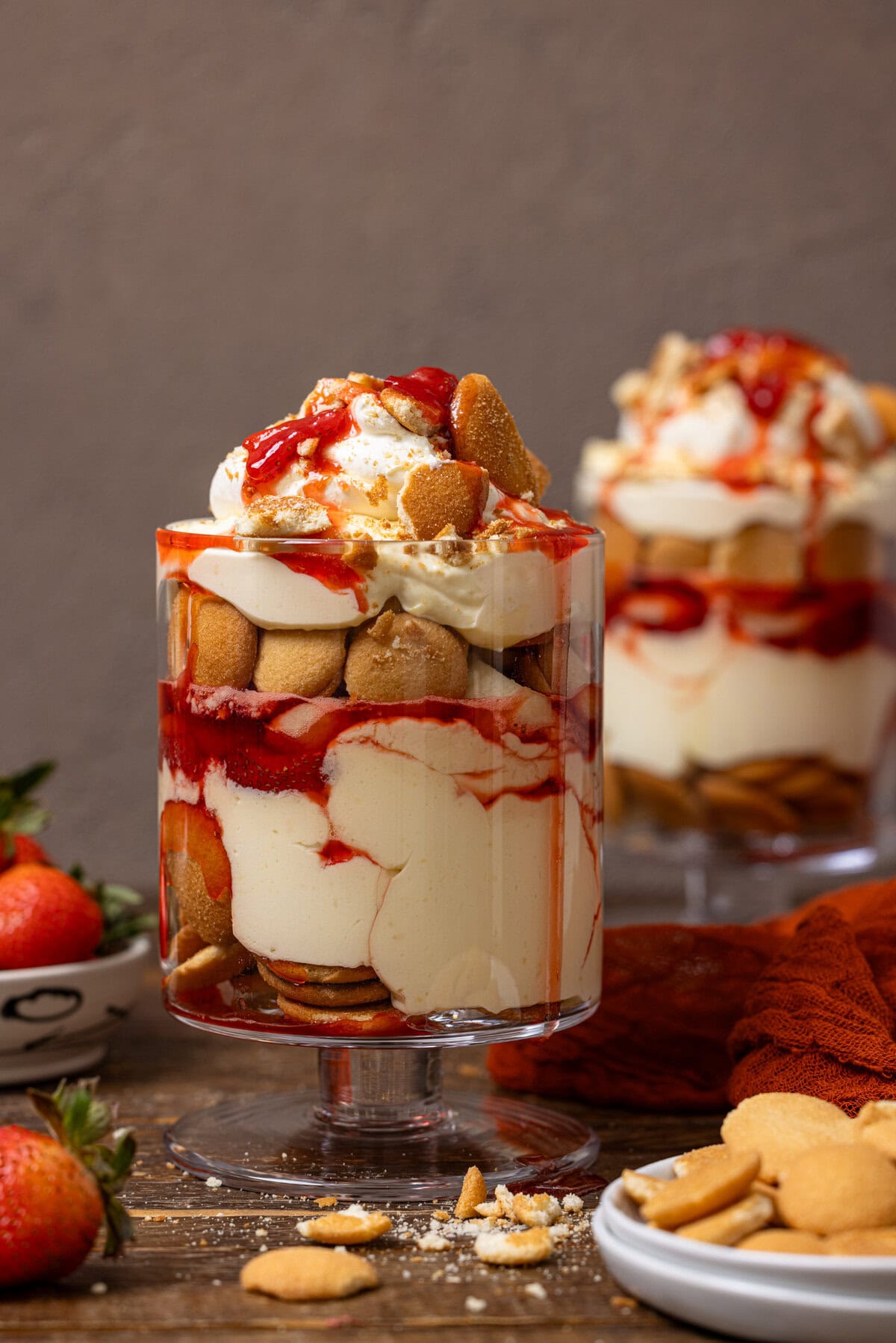 Two trifle bowls of strawberry banana pudding with strawberries and cookies.